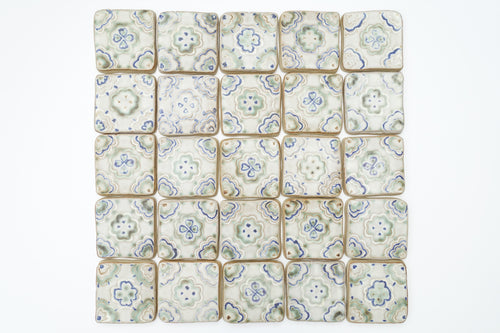 Patterned ceramic tiles arranged in a grid on a white background