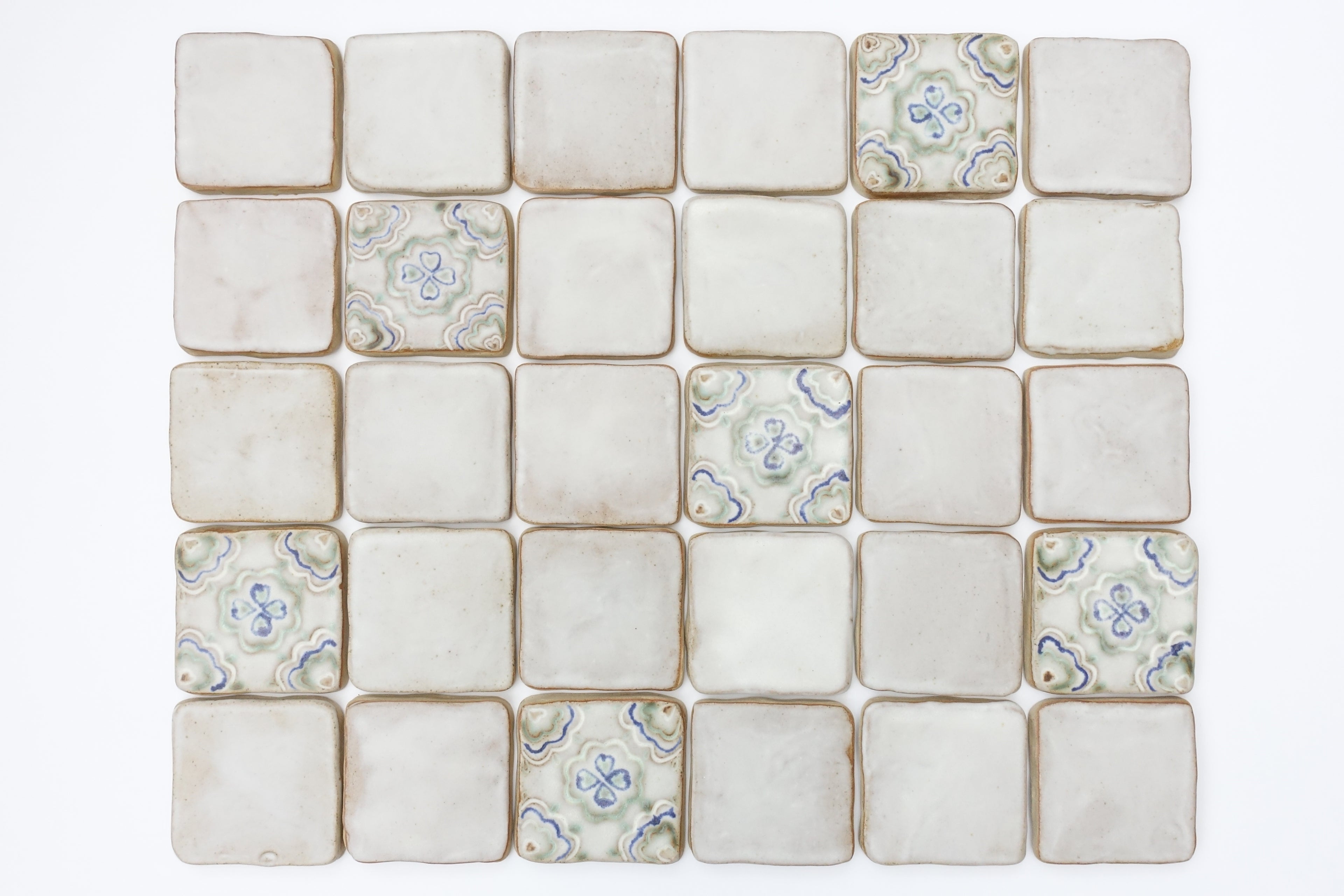 A blend of plain and decorative ceramic tiles on a white background